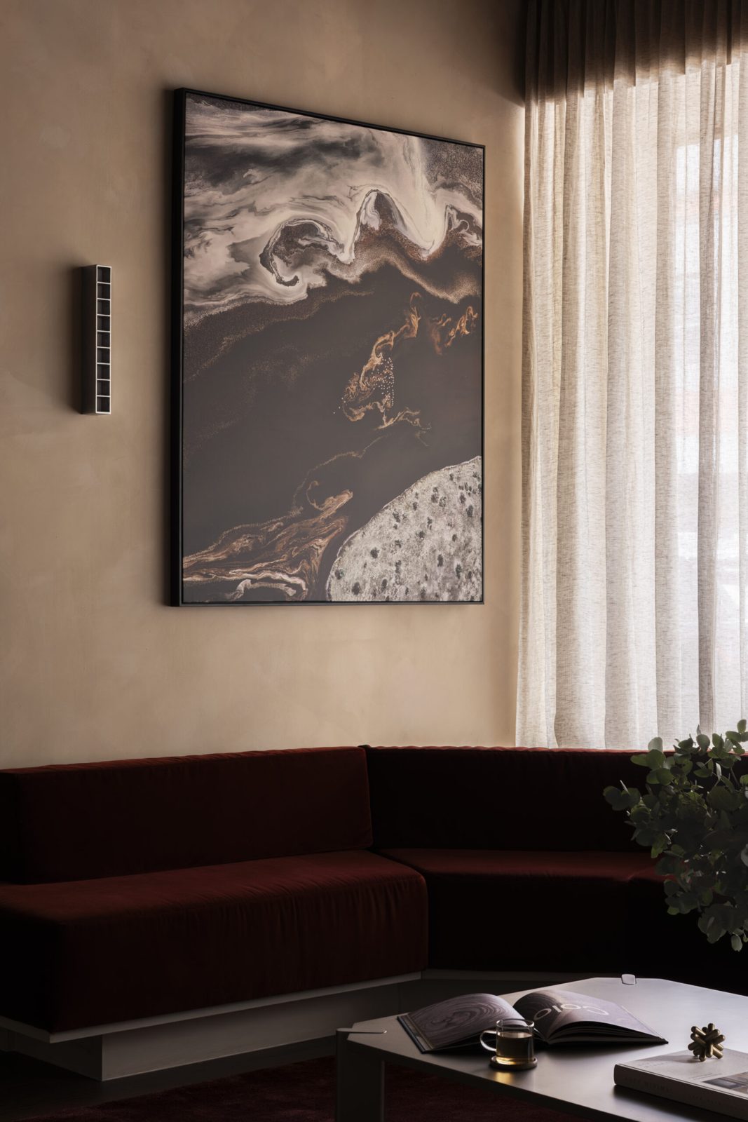 Deep russet velvet lounge beneath artwork by Phillip Chang